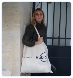 Jeune femme posant devant son domicile avec sac en tissu du pressing à domicile Hublo